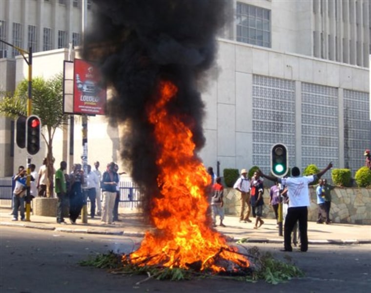 A protester burns vegetation in a street in Lilongwe, Malawi, Wednesday, July 20, 2011. Protesters went on the rampage after a court injunction stopped them protesting the economic and democratic crisis in the country. A coalition of more than 80 rights groups had organised nationwide protest marches for Wednesday. They wanted to protest what they say are moves by the Malawi's President Bingu wa Mutharika to roll back hard-fought democratic gains made since the first democratic polls in 1994 removed dictator Kamuzu Banda from power. (AP Photo/Diane Boles)